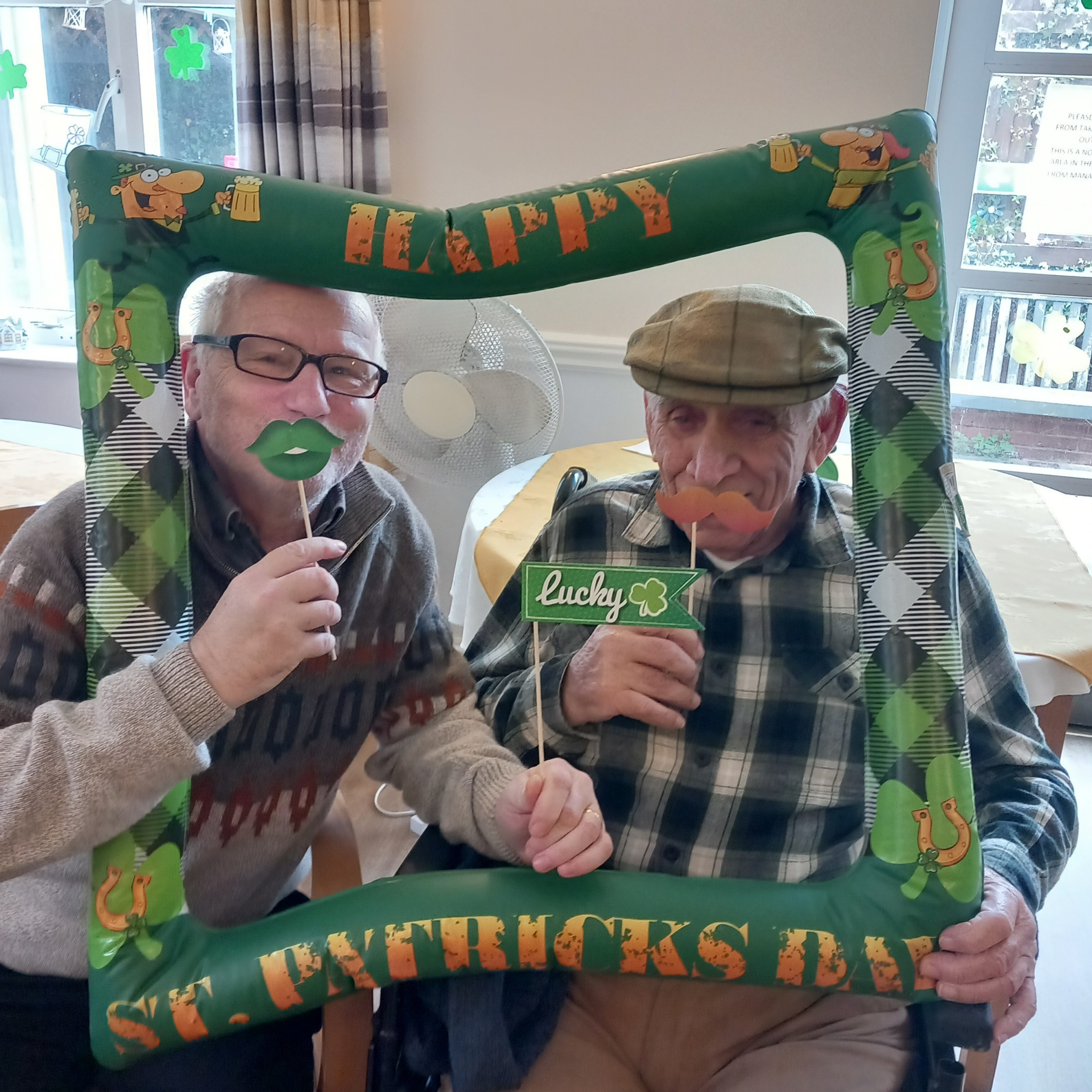 Elderly friends posing with St Patrick's Day green props